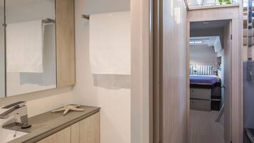 A modern bathroom with a large mirror, a towel rack, a sink, and a starfish decoration.