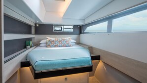 A compact, modern cabin with a bed, built-in storage, and a window offering a view.