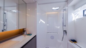 A modern bathroom with a large mirror, a shower, and a sink.