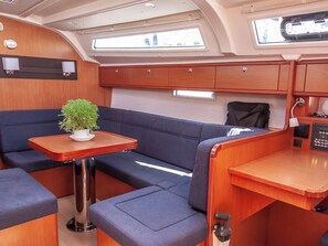 A compact interior with a dining area, seating, and a small table with a plant. - Sun-Kissed Sailing Adventure in the Ionian Islands, Lefkada (Lefkada)