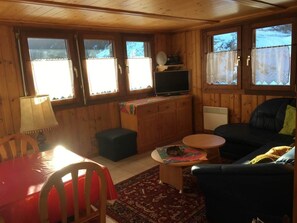A cozy cabin interior with a wooden interior, a television on a stand, a dining table with chairs, and a sofa. - Almenrausch 2. OG Süd-West Appartement/Fewo, Dusche, WC by Interhome (Riederalp)