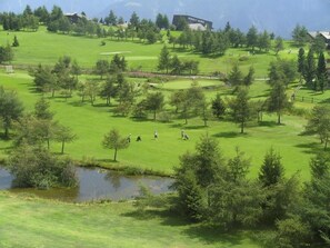 A golf course with trees, a pond, and buildings in the background. - Almenrausch 2. OG Süd-West Appartement/Fewo, Dusche, WC by Interhome (Riederalp)