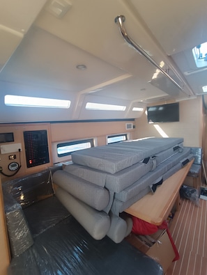 Ein kleines Zimmer mit Bett, Bedienfeld und Fernseher.