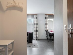 A modern interior with a dining area, a coat rack, and a door leading to another room.