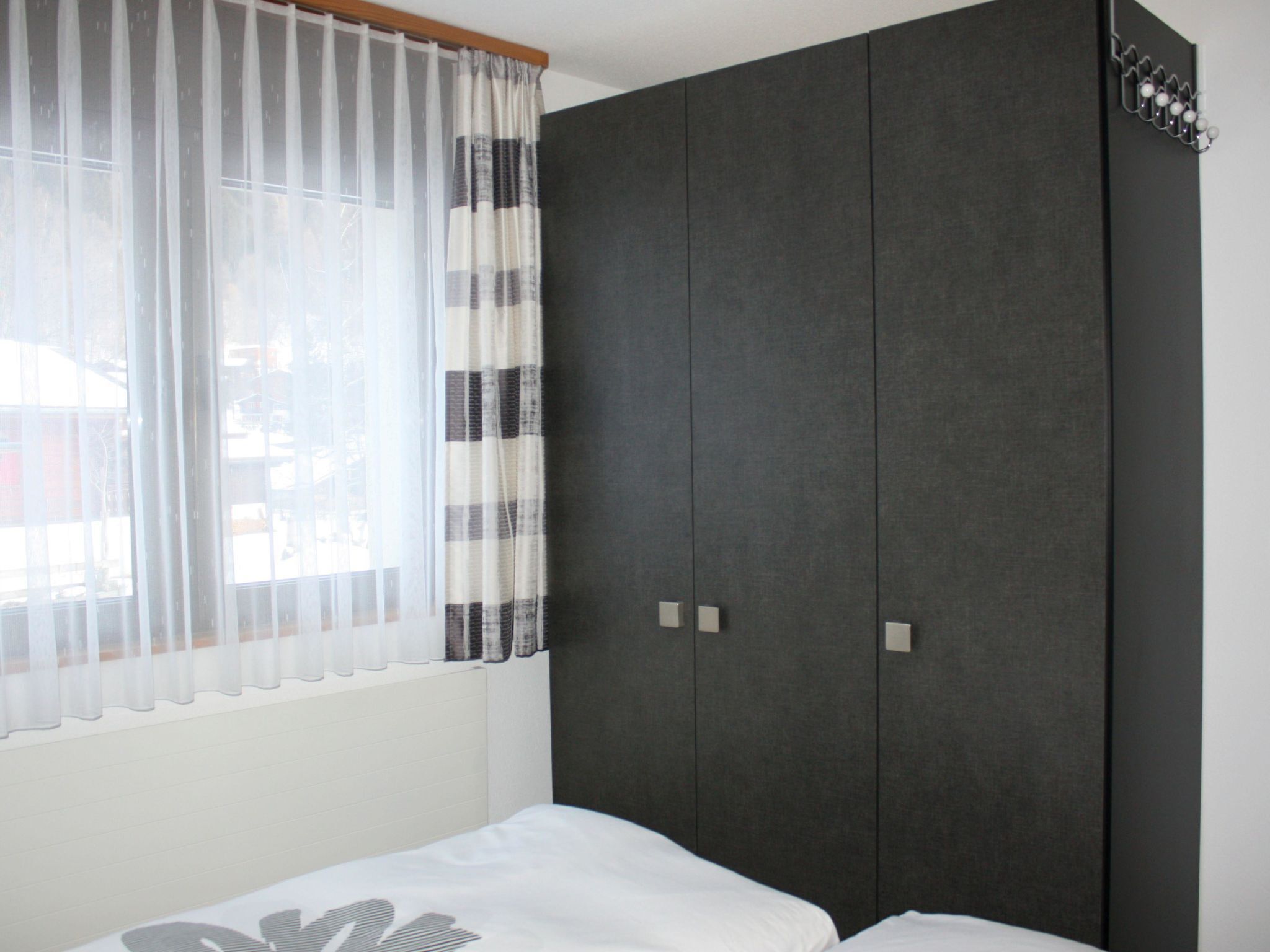Une chambre à coucher avec un lit, une armoire et une fenêtre avec des rideaux.