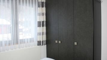 Une chambre à coucher avec un lit, une armoire et une fenêtre avec des rideaux.