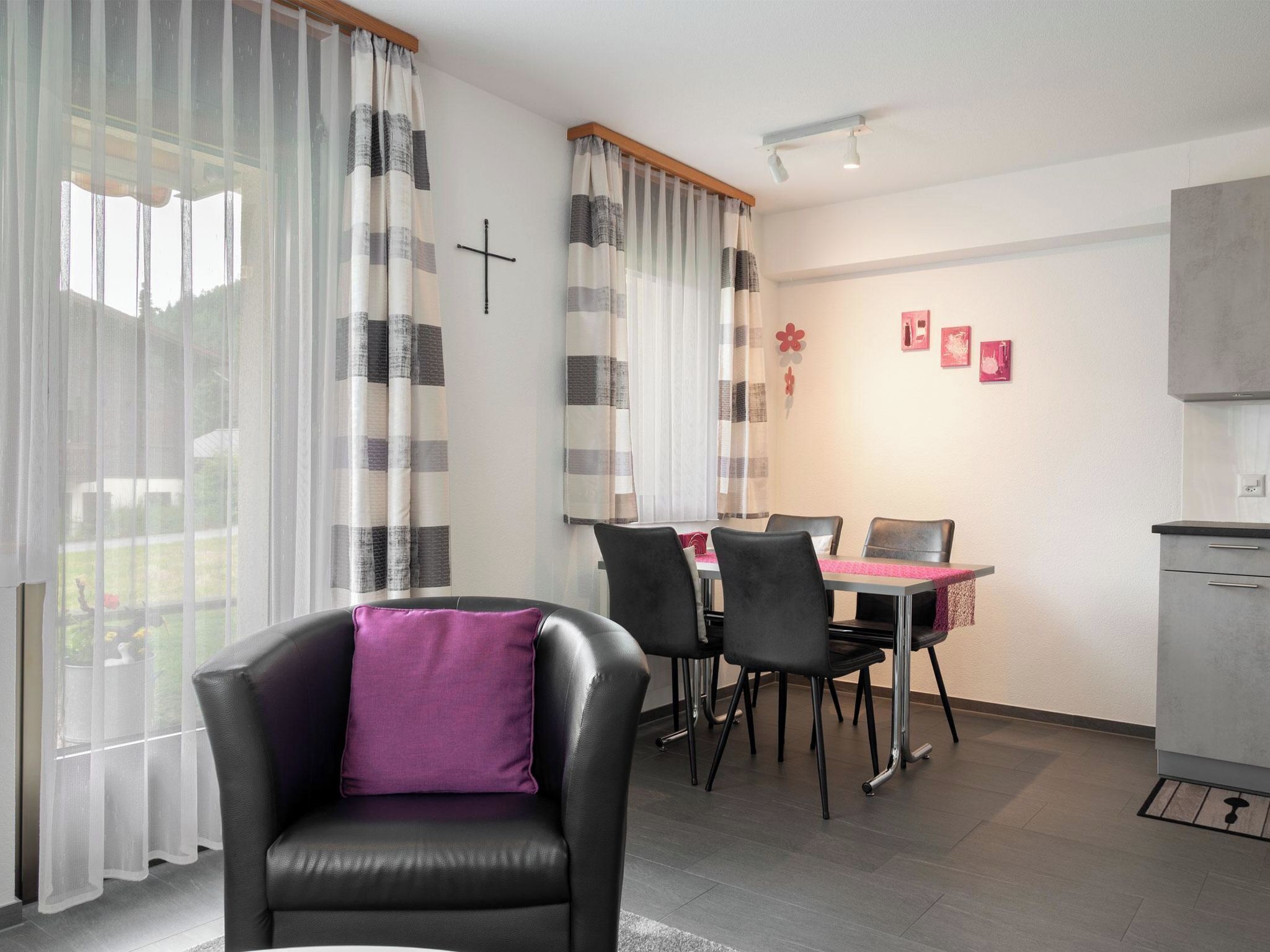 Een moderne woonkamer met een eethoek, met een bank, stoelen, een tafel en een keuken.