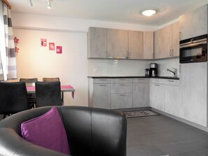 A modern kitchen with grey cabinets, a black countertop, and a Siemens oven.