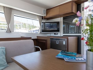 Cocina compacta para autocaravana con microondas, refrigerador y zona de comedor.