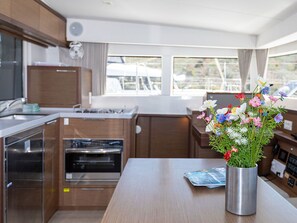 A compact kitchen with built-in appliances, a dining area, and a window with a view of boats. - Sun-Kissed Sailing Adventure in Sibenik, Croatia (Primošten)