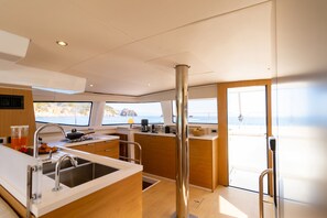 A modern kitchen with a stainless steel sink, wooden cabinets, and a view of the sea through large windows. - Sun-kissed Sailing Adventure in the Ionian Islands (Preveza)
