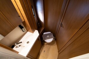 Un baño pequeño con lavamanos, inodoro y muebles de madera.