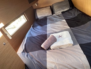 A bed with a checkered bedspread, a rolled towel, and a starfish pillow. - Sun-Kissed Sailing Adventure in Islas Sarónicas (Alimos)