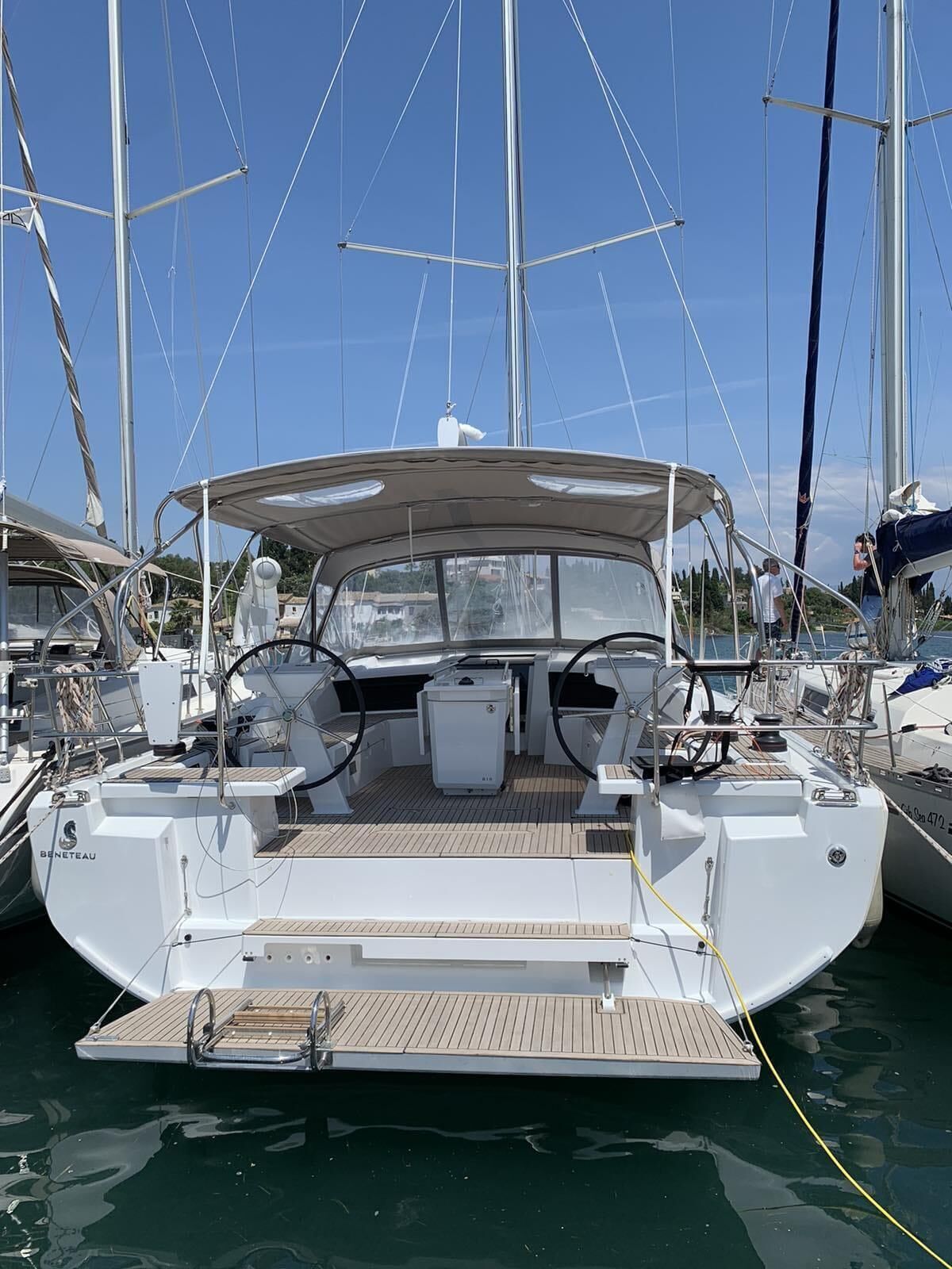 A sailboat docked at a marina with a covered deck, steering wheel, and winches.