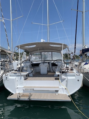 Eine Segelyacht liegt in einer Marina festgemacht, mit überdachter Deckfläche, Steuer und Winschen.
