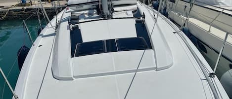 Eine Segelyacht liegt an einem Hafensteg mit überdachtem Deck und einer Kabine.