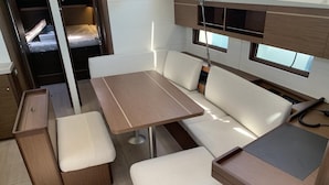Interior compacto de uma RV, com área de refeições, assentos e uma pequena cozinha.
