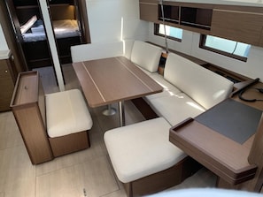 Ein kompaktes Wohnmobil-Interieur mit Essbereich, Sitzgelegenheiten und einer kleinen Küchenzeile.