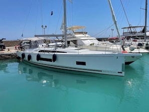 A white yacht docked at a marina with clear turquoise water.