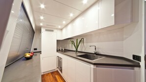 A modern kitchen with white cabinetry, a black countertop, and a stainless steel sink. - Sun-Kissed Sailing Adventure in Zadar, Croatia (Drage)