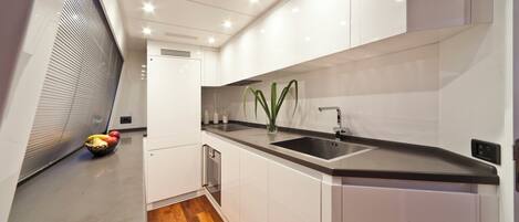 A modern kitchen with white cabinetry, a black countertop, and a stainless steel sink.