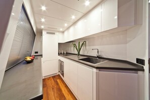 A modern kitchen with white cabinetry, a black countertop, and a stainless steel sink. - Sun-Kissed Sailing Adventure in Zadar, Croatia (Drage)
