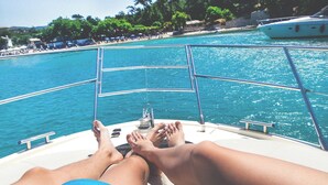 Um barco com corrimão de metal e uma pessoa relaxando com os pés apoiados.