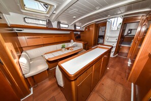 A compact galley with a central dining table, a cushioned seating area, and a small kitchenette. - Sun-Kissed Sailing Adventure in Zadar, Croatia (Bibinje)