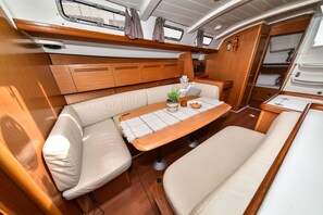 A boat interior with a cushioned seating area, a small table with a plant, and a compact kitchenette. - Sun-Kissed Sailing Adventure in Zadar, Croatia (Bibinje)