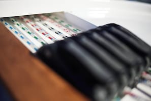 A close-up of a black, ribbed object, possibly a part of furniture or equipment, with a blurred background.