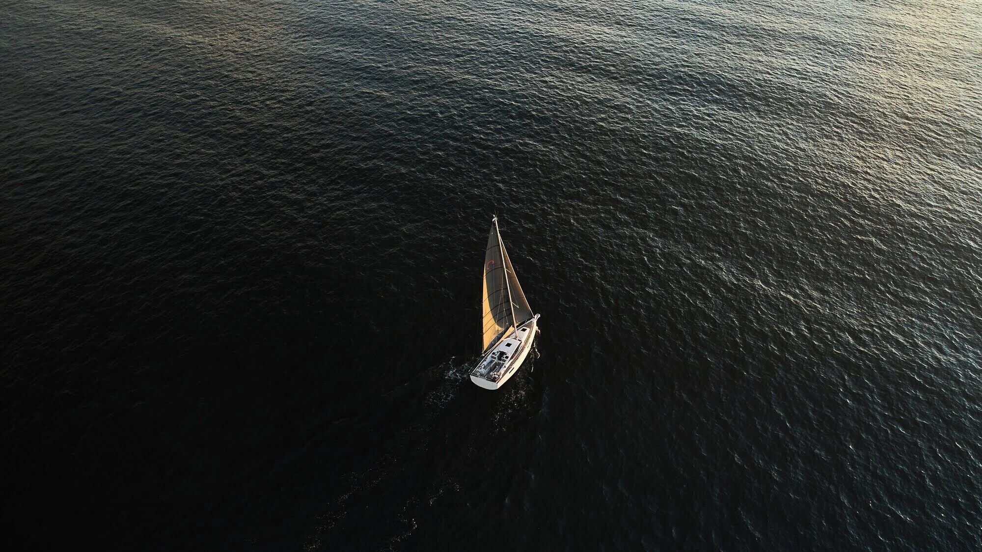Vue aérienne d’un voilier sur une eau calme.