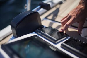 A boat's control panel with a hand operating a device.