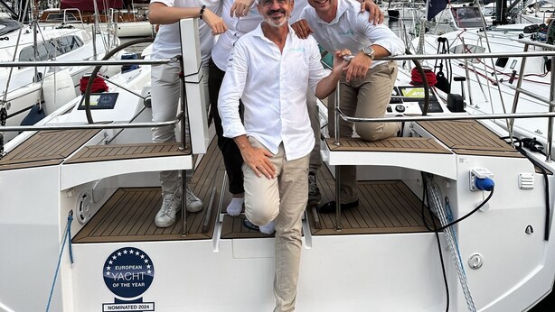 Eine Gruppe von Menschen auf einer Yacht, wobei eine Auszeichnung 'European Yacht of the Year' zu sehen ist.