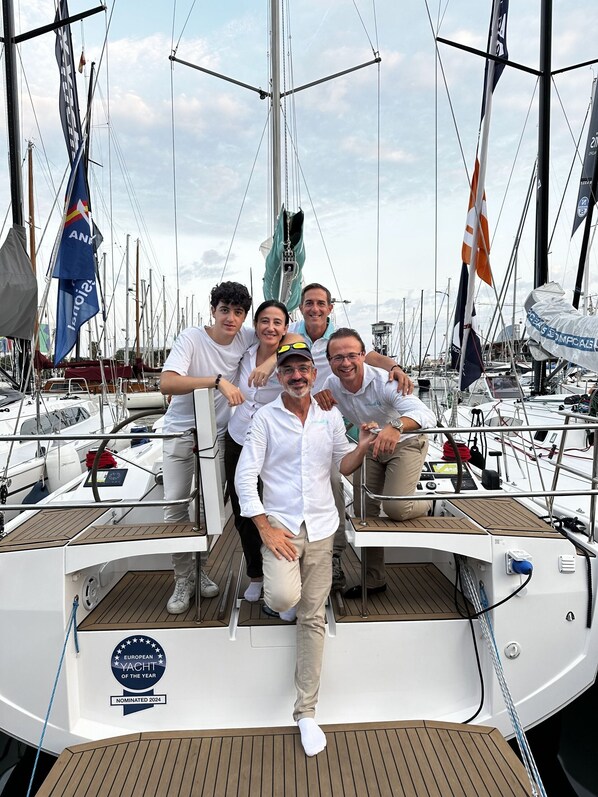 Eine Gruppe von Menschen auf einer Yacht, wobei eine Auszeichnung 'European Yacht of the Year' zu sehen ist.