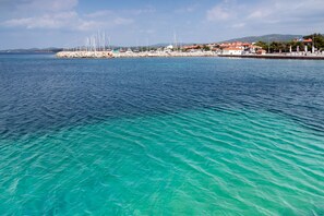 A coastal marina with boats, a rocky breakwater, and buildings with red roofs. - Sun-Kissed Sailing: A Luxurious Beach Experience in Nikiti, Macedonia (Nikiti)