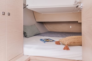 A compact, well-organized sleeping area with a bunk bed, a pillow, a book, and a blanket.