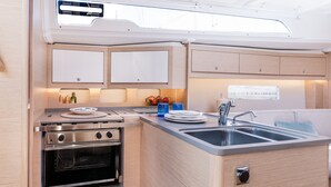 A compact kitchenette with a stove, oven, sink, and cabinets. - Sun-Kissed Sailing Adventure in the Ionian Islands, Lefkada (Lefkada)