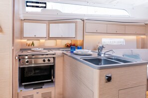 A compact kitchenette with a stove, oven, sink, and cabinets. - Sun-Kissed Sailing Adventure in the Ionian Islands, Lefkada (Lefkada)