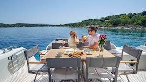 Un bote con mesa lista para dos personas, rodeado de agua y follaje.