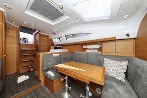 Um espaço interior pequeno e bem iluminado, com mesa de madeira, assentos acolchoados e armários para guardar objetos.