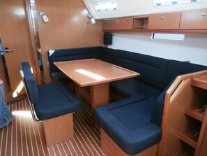 A compact galley with a wooden table, blue cushioned seating, and a small cabinet. - Sun-Kissed Sailing Adventure in the Ionian Islands, Lefkada (Lefkada)