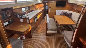 A compact galley with a wooden table, bench seating, a small kitchenette, and a mounted TV. - Sun-Kissed Sailing Adventure in Sibenik, Croatia (Rogoznica)