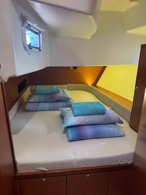 Une petite cabine équipée d’un lit superposé, d’une petite fenêtre et d’une tête de lit en bois.