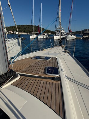 A boat deck with a white railing, a sunshade, and a view of other boats in the marina. - Sun-Kissed Sailing Adventure in Sibenik, Croatia (Rogoznica)