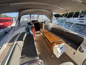 Ein Bootsdeck mit Holztisch, gepolsterten Sitzgelegenheiten und einem B&G Kühler.