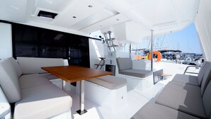 En lyxig inredning på en yacht med ett matområde, sittplatser och utsikt över hamnen.