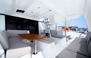 A yacht interior with a dining area, seating, and a view of the marina. - Sun-Kissed Sailing Adventure in the Ionian Islands, Lefkada (Lefkada)