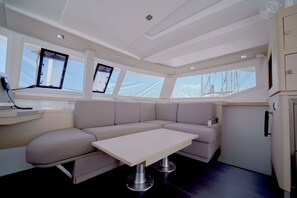 A modern interior with a sofa, table, and windows overlooking the sea. - Sun-Kissed Sailing Adventure in the Ionian Islands, Lefkada (Lefkada)