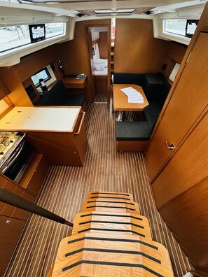 A compact interior with a dining area, seating, and a small kitchenette. - Sun-Kissed Sailing Adventure in Northern Croatia (Novi Vinodolski)