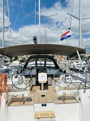 A boat deck with a steering wheel, a control panel, and a flag. - Sun-Kissed Sailing Adventure in Northern Croatia (Novi Vinodolski)